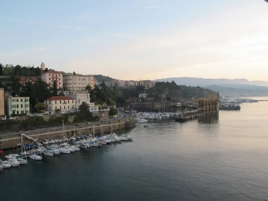 A quiet bay at dusk with villas on the hillside and boats moored along the shore.