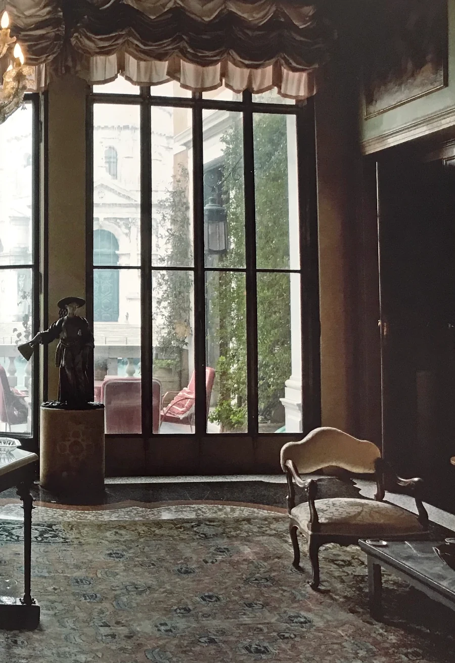 A piano nobile salon, tall glazed doors opening to a balustraded terrace above the city.